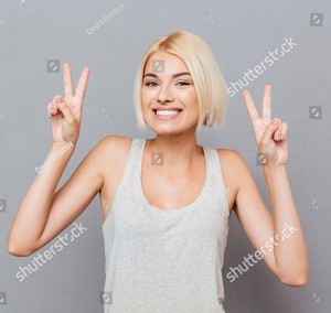 stock-photo-cheerful-cute-young-woman-showing-peace-sign-with-both-hands-over-gray-background-479011873.jpg