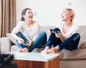stock-photo-two-laughing-girlfriends-playing-video-games-with-joystick-418968217.jpg