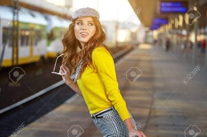 63287582-belle-jeune-femme-avec-une-valise-est-en-attente-d-un-train.jpg