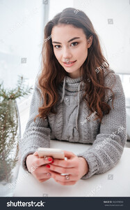 stock-photo-image-of-happy-young-woman-dressed-in-sweater-sitting-in-cafe-at-cold-winter-day-chatting-by-phone-562478056.jpg