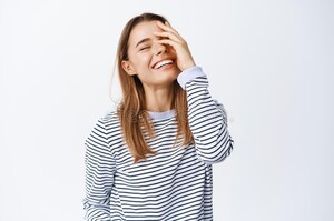 happy-young-woman-touching-covering-half-face-laughing-sincere-having-fun-feeling-positive-standing-upbeat-against-white-212511634.jpg