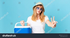 stock-photo-pretty-red-head-woman-smiling-and-looking-friendly-showing-number-two-and-holding-a-portable-2100708898.jpg