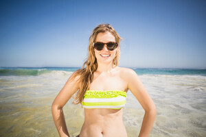 21724898_pretty-woman-in-bikini-and-sunglasses-standing-on-the-beach.jpg