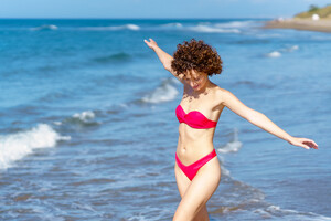 52603146_joyful-young-lady-in-swimwear-walking-in-sea-with-outstretched-arms.jpg