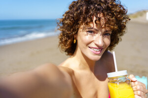 53055468_cheerful-woman-enjoying-juice-and-taking-self-portrait-on-beach.jpg