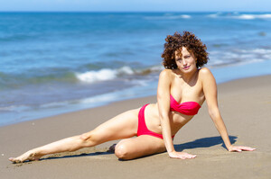 53055478_curly-woman-in-swimsuit-lying-on-sandy-beach.jpg