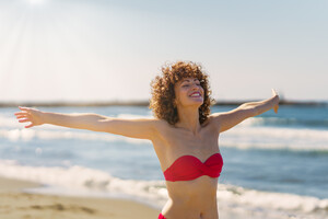 53055578_happy-woman-in-bikini-standing-on-beach.jpg