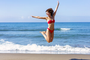 53336926_happy-woman-in-bikini-jumping-in-air-on-beach.jpg
