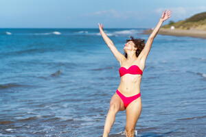 53729308_carefree-woman-in-bikini-with-raised-arms-at-beach.jpg