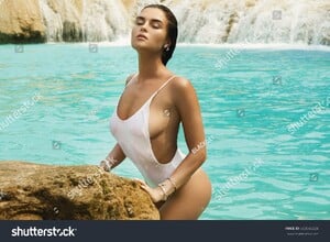 stock-photo-sexy-woman-in-white-swimsuit-is-posing-on-the-rock-beside-beautiful-waterfall-with-blue-water-663548224.jpg