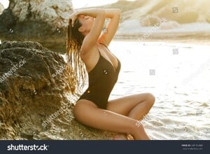 stock-photo-sexy-woman-on-the-beach-with-rocks-at-sunset-604186484.jpg