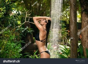 stock-photo-sexy-woman-wearing-black-bikini-taking-shower-in-tropical-garden-in-resort-1115890382.jpg