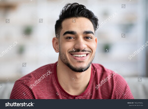 stock-photo-closeup-portrait-of-cheerful-handsome-arab-guy-smiling-at-camera-while-chilling-at-home-copy-space-1982470382.jpg