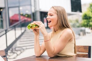 pretty-young-woman-eating-hamburger-outdoor-street.jpg